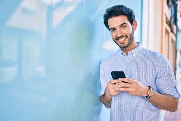 Молодий Іспаномовний Чоловік Посміхається Щасливий Використовуючи Смартфон Спирається Стіну — стокове фото