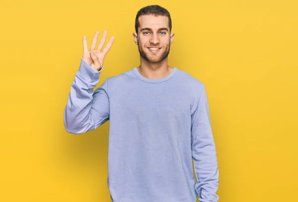 自信と幸せな笑顔ながら カジュアルな服を着て指の数4で上を指す若い白人男性 — ストック写真