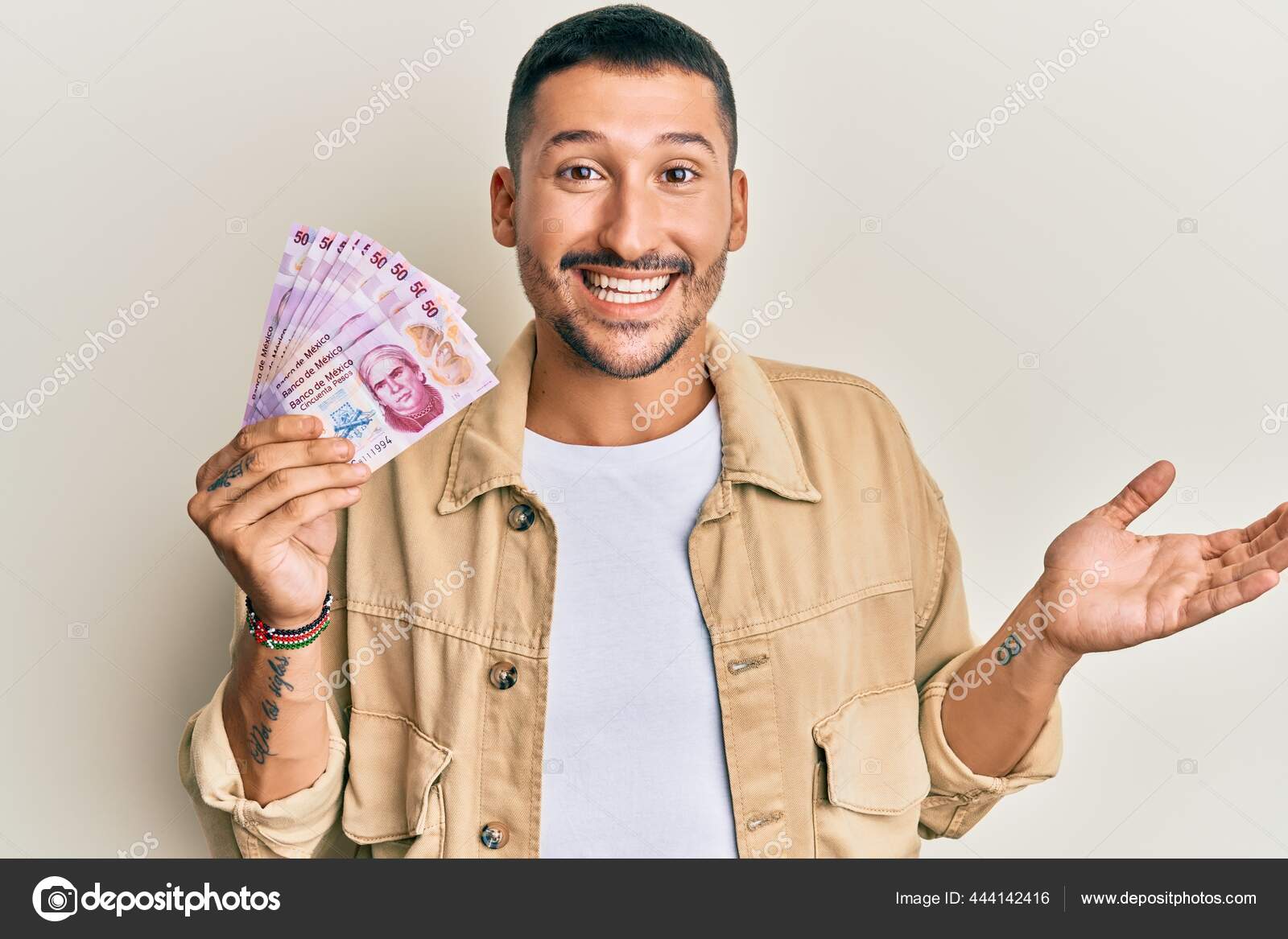 英俊的男子手持50枚墨西哥比索钞票笑容满面高举双手庆祝胜利——图库图片© Krakenimages.com #444142416