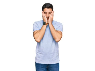 Günlük kıyafetler giyen genç İspanyol adam yorgun eller yüzünü kapatıyor, depresyon ve üzüntü, sorun yüzünden üzgün ve sinirli. 