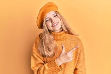 Fransız elbisesi giyen güzel, beyaz bir kız. Yüzünde mutlu ve doğal bir ifadeyle, elleri ve parmaklarıyla yüzünü gösteren bir gülümseme ile neşeli bir bere takın. 