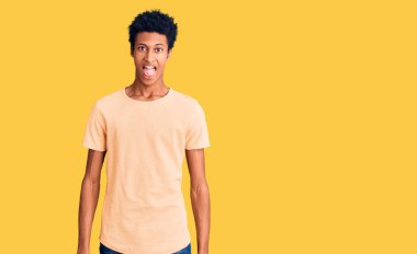 Genç, Afro-Amerikan bir adam günlük kıyafetler giyiyor. Dilini komik bir ifadeyle dışarı çıkarıyor. duygu kavramı. 