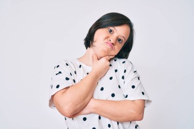 Down sendromlu esmer kadın gündelik giysiler giyip kollarını kavuşturarak depresyondan sıkılmış ve yorgun görünüyor.. 