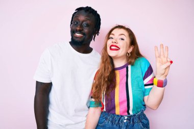 Irklar arası bir çift günlük kıyafetler giyer ve üç numaralı parmaklarıyla gülümseyerek mutlu ve kendinden emin görünürler.. 