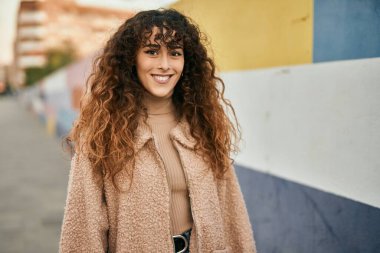 Genç İspanyol kadın gülümseyerek şehirde mutlu mesut dikiliyor.