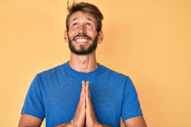 Yakışıklı, sakallı, sıradan kıyafetler giyen, elleri bağlı yalvaran ve dua eden, yüzünde umut ifadesi olan çok duygusal ve endişeli bir beyaz adam. Yalvarıyor. 