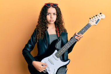 Genç İspanyol kız elektro gitar çalıyor. Depresyonda ve üzüntüden ağlıyor. Kızgın ve korkmuş. hüzünlü ifade. 