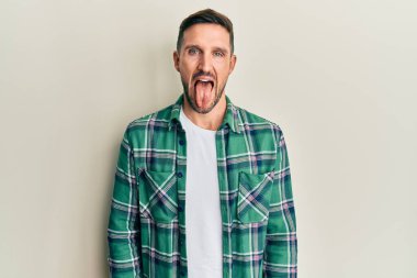 Sakallı, sıradan kıyafetler giyen, dilini dışarı çıkaran, komik ifadeli yakışıklı bir adam. duygu kavramı. 