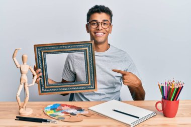 Genç ve yakışıklı Afrikalı Amerikalı ressam sanat stüdyosunda boş bir çerçeve tutuyor. 