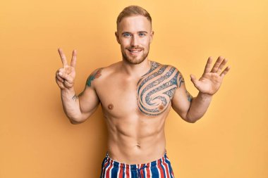 Mayo giyen genç, beyaz bir adam yedi numaralı parmaklarıyla gösteriş yapıyor ve gülümsüyor. Kendinden emin ve mutlu.. 