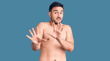 Mayo giyen genç yakışıklı adam korkudan dehşete düşmüş ve dehşete düşmüş. El hareketlerini durdur, şok içinde bağır. panik konsepti. 