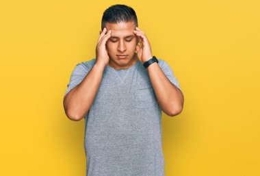 Stres yüzünden başı ağrıyan gündelik kıyafetler giyen genç Latin bir adam. migren ağrısı. 