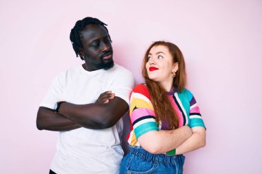 Irklar arası çift, sıradan kıyafetler giyip kollarını kavuşturup yan tarafa bakıyor. İkna olmuş ve kendinden emin. 