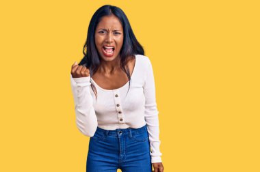 Kızgınlık ve kızgınlık içinde genç Hintli bir kız öfkeyle bağırırken yumruğunu sallıyor ve öfkeleniyor. öfke ve agresif konsept. 