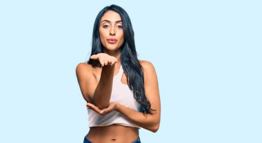 Güzel İspanyol kadın, gündelik kıyafetler giyip kameraya bakıyor. Elini havaya kaldırarak öpüşüyor. Sevimli ve seksi. aşk ifadesi. 