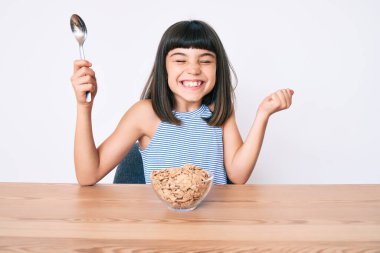 Bangır bangır oturmuş mısır gevreği yiyor gururla bağırıyor, zaferi kutluyor ve kollarını kaldırarak başarıyı kutluyor. 