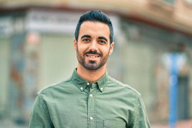 Genç İspanyol adam gülümseyerek şehirde mutlu mesut dikiliyor..