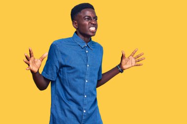 Genç, Afro-Amerikalı, günlük kıyafetler giymiş çılgın ve kızgın bir şekilde bağırıyor, agresif bir ifade ve kollarla bağırıyor. hüsran kavramı. 