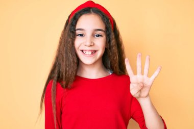 Sevimli İspanyol çocuk gündelik giysiler giyip dört numaralı parmaklarıyla işaret ederken kendinden emin ve mutlu bir şekilde gülümsüyor.. 