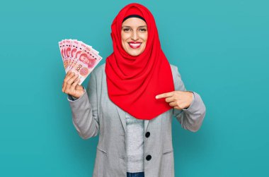 Güzel İspanyol kadın, elinde Çin Yuan banknotlarıyla mutlu ve gururlu gülümseyen bir kişiyi işaret ediyor. 