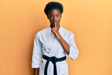 Karate kimonosu ve siyah kuşak giyen genç Afrikalı Amerikalı kız sessiz olmak istiyor. sessizlik ve gizli konsept. 