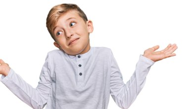 Sıradan kıyafetler giyen, kafası karışmış, kolları ve elleri havada beyaz bir çocuk. şüphe kavramı. 