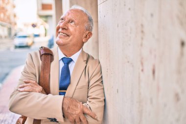 Kıdemli gri saçlı işadamı şehirde mutlu mesut dikiliyor..