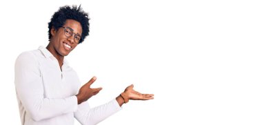 Afro saçlı, sıradan giyinmiş ve gözlüklü yakışıklı Afro-Amerikalı adam gülümseyerek içeri girmeye davet ediyor. 