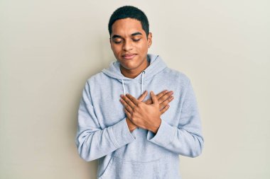 Genç, yakışıklı, sıradan bir kazak giyen, elleri göğsünde, gözleri kapalı, yüzünde minnet dolu bir jest ile gülümseyen bir İspanyol. sağlık kavramı. 