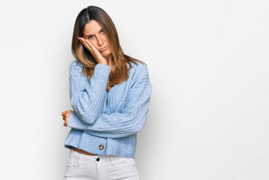 Gündelik giysiler giyen genç bir kadın kollarını kavuşturarak depresyondan yorgun ve sıkılmış göründüğünü düşünüyor.. 