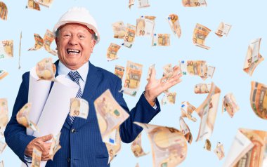 Kıdemli yakışıklı, gri saçlı mimar şapkalı adam elinde zaferi mutlu bir gülümsemeyle ve ellerini kaldırarak kutlayan planlar tutuyordu.