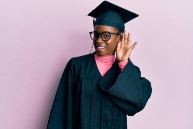 Mezuniyet şapkası ve tören cübbesi takan genç Afro-Amerikan kız. Kulaktan kulağa gülüyor. Dedikoduları ve dedikoduları dinliyor. Sağırlık kavramı. 