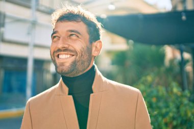 Zarif ceket giyen yakışıklı iş adamı dışarıda mutlu bir şekilde gülümsüyor.