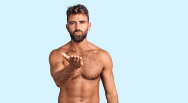 Mayo giyen genç İspanyol bir adam kameraya bakıp havada el sallıyor ve sevimli ve seksi oluyor. aşk ifadesi. 