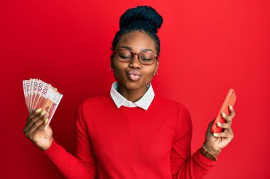 Genç Afro-Amerikalı kadın elinde Norveç Kronu banknotları tutarak kameraya bakıyor. Öpücük atıyor ve çok seksi. aşk ifadesi. 