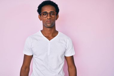 Sıradan kıyafetler giyen ve yüzünde ciddi bir ifade olan Afrikalı yakışıklı bir adam. Basit ve doğal bir şekilde kameraya bakıyorsun.. 