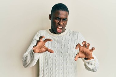 Genç Afro-Amerikan adam günlük kıyafetler giymiş komik gülüyor kedi gibi pençe hareketi yapıyor, agresif ve seksi bir ifade. 