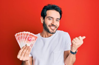 Genç İspanyol adam elinde 20 İsrail şekeri tutuyor. Banknotlar gururla haykırıyor, zaferi ve başarıyı kutluyor. 