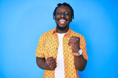 Saçları örgülü genç Afro-Amerikalı adam kolları havada ve gözleri kapalı bir şekilde başarıyı kutluyor. 