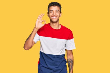 Genç, yakışıklı, Afro-Amerikalı günlük kıyafetler giyen, gülümseyen, el ve parmaklarıyla 