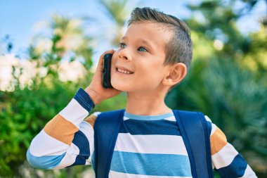 Sevimli beyaz çocuk gülümsüyor. Parktaki akıllı telefondan konuşuyor..