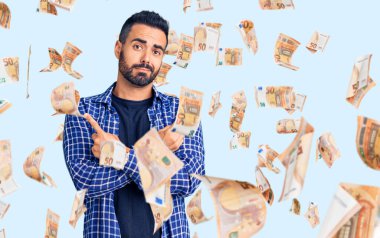 Gündelik kıyafetler giyen genç İspanyol adam her iki tarafı da parmaklarıyla işaret ediyor, farklı yönlerde farklı görüşler.