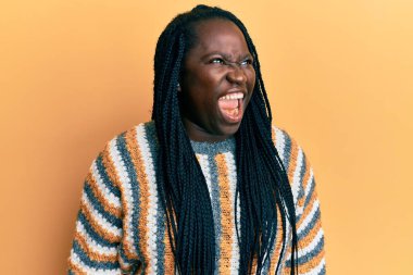 Saçları örgülü genç siyah bir kadın. Öfkeli ve öfkeli bir şekilde bağırıyor. Öfkeyle bağırıyor. öfke ve agresif konsept. 