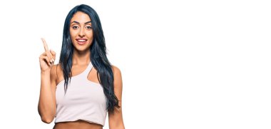 Gündelik kıyafetler giyen güzel İspanyol kadın başarılı bir fikirle işaret ediyor. Heyecanlı ve mutlu. Bir numara.. 