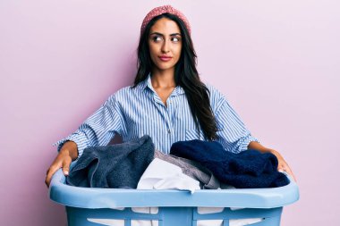 Güzel İspanyol kadın çamaşır sepetini tutuyor gülümsüyor ve yan tarafa bakıyor ve düşünüyor.. 