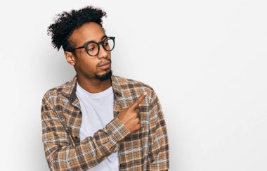 Sakallı, sıradan giyinmiş ve gözlüklü genç Afro-Amerikan bir adam. Elle işaret ediyor, ciddi ve sakin bir yüz ifadesi var. 