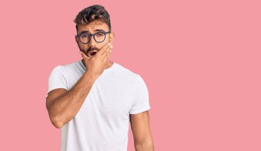 Gündelik giysiler ve gözlük takan genç İspanyol adam inançsızlıktan, şaşkınlıktan ve elleri çenesinde olan şaşkınlıktan büyülenmiş gibi görünüyor. 