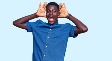 Genç Afro-Amerikalı günlük kıyafetler giymiş neşeli gülümseyen ve elleri havada bir böceği dikizleyen bir adam. Şaşırdım ve çıktım. 