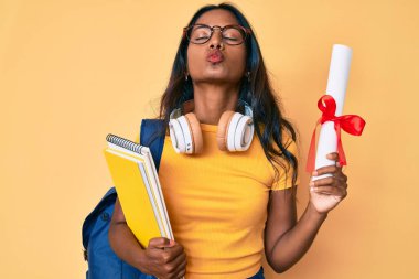 Sırt çantalı genç Hintli kız. Elinde diplomayla kameraya bakıyor. Öpüşme sahnesine bakıyor. aşk ifadesi. 