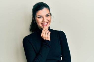 Gündelik kıyafetler giyen genç İspanyol kadın kameraya kollarını kavuşturmuş ve çenesi üzerinde kendinden emin bir şekilde bakıyor. Olumlu düşünmek. 